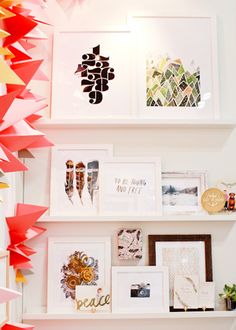 several framed pictures and paper cranes hanging on the wall in a room with white walls