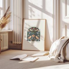 an art work is displayed on the floor next to a pillow and pillows in front of a window