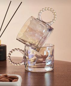 a glass cup filled with some kind of liquid on top of a table next to a bowl