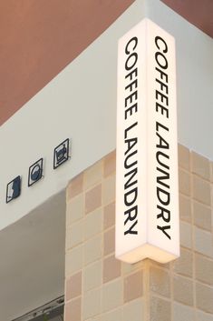 there is a sign that says coffee laundry on the side of a building with lights above it