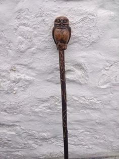 an owl head on top of a black pole in front of a white wall and cement floor