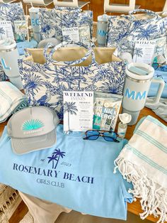 various items are laid out on a table with blue and white towels, hats, sunglasses, and other items