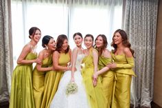 a group of women standing next to each other in front of a curtained window