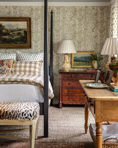 a bed sitting in a bedroom next to a wooden dresser and table with a lamp on top of it