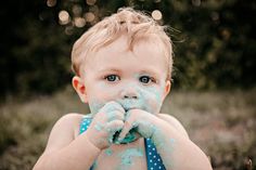 a little boy covered in blue and white paint eating something out of his hands while standing outside