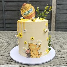 a winnie the pooh cake with flowers and honey on top is sitting on a table