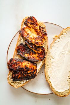 two pieces of bread on a plate with cream cheese and chicken breast patties in the middle