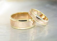 two gold wedding rings sitting next to each other