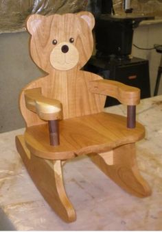 a wooden teddy bear sitting on top of a wooden chair