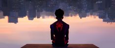 a man sitting on top of a wooden bench in front of a city