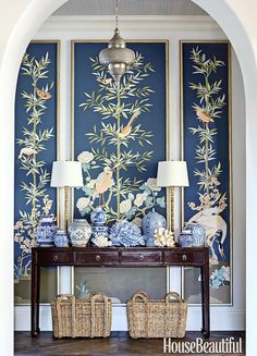 a table with two lamps on top of it next to a wall covered in flowers and birds