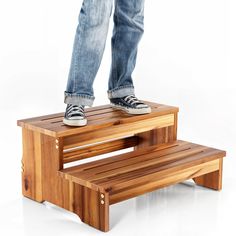 a person standing on a wooden bench with their feet on the bench and legs crossed