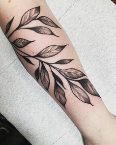 a black and white leaf tattoo on the arm