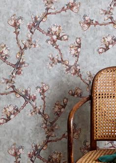 a chair sitting in front of a wallpapered with flowers and branches on it