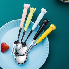 five different colored utensils on a blue plate with strawberries in the background