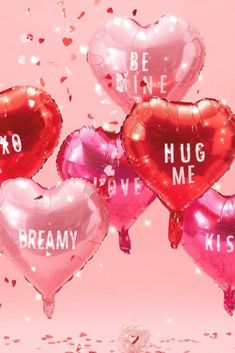 pink and red heart shaped balloons with the words hug me, kiss me on them