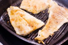 two pieces of fish are cooking in a frying pan on the stove top,