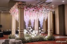 an elaborately decorated stage with pink flowers and greenery on the ceiling is lit up