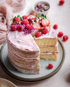 a layered cake with strawberries and flowers on top is cut from the rest of the cake