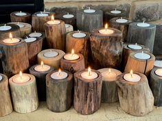 many wooden candles are lit in front of a brick wall