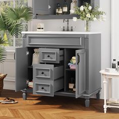 a gray bathroom vanity with drawers and white counter top next to a potted plant