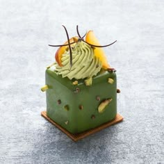 a dessert with green frosting and fruit toppings in a square dish on a table