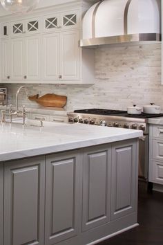 a kitchen with white cabinets and marble counter tops