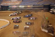 several dirt racing cars driving around a track