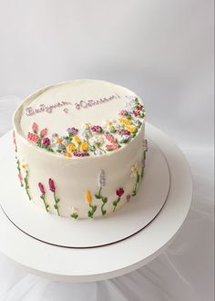 a white cake decorated with flowers and the words happy birthday on it's side