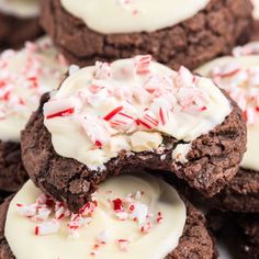 chocolate cookies with white frosting and candy canes on top are stacked together in a pile