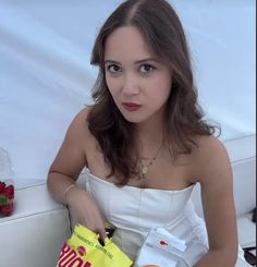 a woman in a white dress is holding a bag and some strawberries on the table