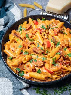 a bowl filled with pasta and meat on top of a blue table cloth next to utensils