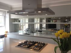 an image of a kitchen setting with flowers in the foreground and yellow tulips on the counter