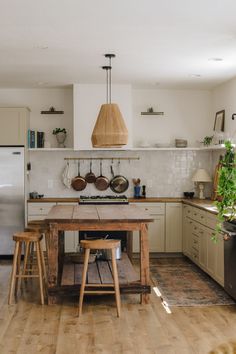 a kitchen with wooden stools and an island in the middle, surrounded by potted plants