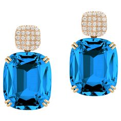 Introducing the stunning London Blue Topaz Cushion & Diamonds Earrings from our popular 'Gossip' Collection. The focal point of these earrings is the mesmerizing London Blue Topaz cushion-cut gemstone. The cushion-cut shape adds a touch of vintage charm, while the vibrant color of the London Blue Topaz exudes a captivating allure. The gemstone is carefully faceted to enhance its brilliance and maximize its natural beauty. O the top of the London Blue Topaz gemstone you can find dazzling diamonds, which add a touch of sparkle and sophistication to the overall design. The diamonds are meticulously set in 18K yellow gold, creating a beautiful contrast against the London Blue Topaz. The craftsmanship of these earrings is impeccable, with attention to detail evident in every aspect. With their Cushion Cut Diamond Earrings, Emerald Cut Diamond Earrings, Cushion Earrings, Blue Topaz Stone, Blue Topaz Earrings, Cushion Cut Diamonds, Topaz Earrings, Unique Diamonds, Topaz Stone