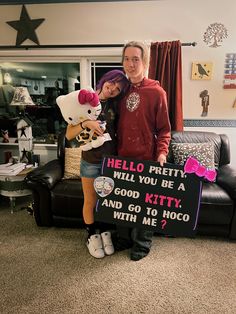 a man and woman standing next to each other in front of a couch with a hello kitty sign on it