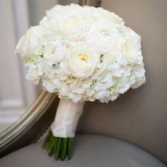 a bouquet of white flowers sitting on top of a gray chair next to a mirror