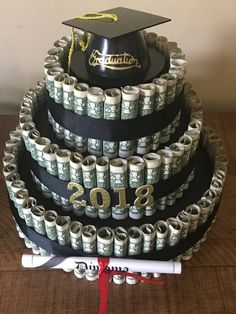 a graduation cake made out of stacks of money and rolled up diploma caps on top