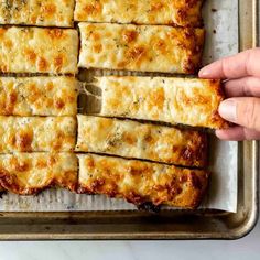 someone is holding up some food on a baking sheet in the middle of their meal