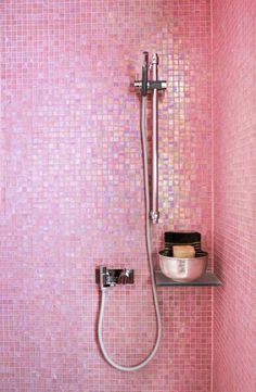 a pink tiled bathroom with a shower head