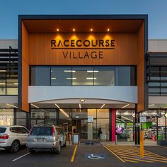 a large building with cars parked in front of it and the words race course village