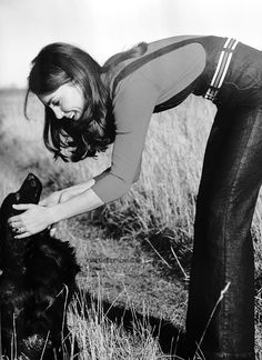 a woman is petting a dog in the grass