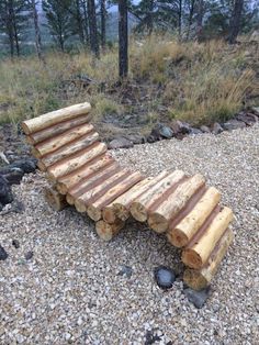 a wooden bench made out of logs on gravel