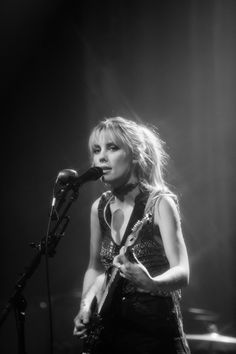 a woman standing in front of a microphone on stage