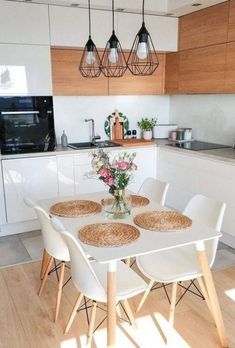 a white table with four chairs and a vase filled with flowers on top of it