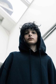 a young man wearing a hoodie standing in front of an escalator