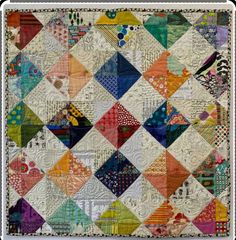 an old quilt with many different colors and patterns on the front, along with a white border