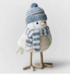 a small stuffed bird wearing a blue and white striped hat, scarf and mittens