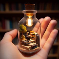 a person holding a miniature light bulb in their hand with books on the shelves behind them