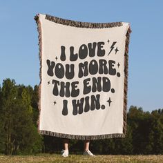 a woman holding up a white and black blanket that says i love you more the end, i win